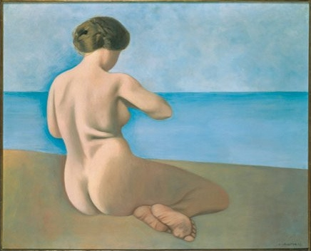 Bagnante bionda seduta di spalle sulla sabbia